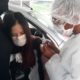 Na imagem, Maria Fernanda Linhares, adolescente com síndrome de down sendo vacinada contra a Covid-19