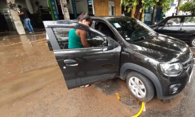 Moradora do bairro do Maracanã limpando o carro após fortes chuvas atingirem a região