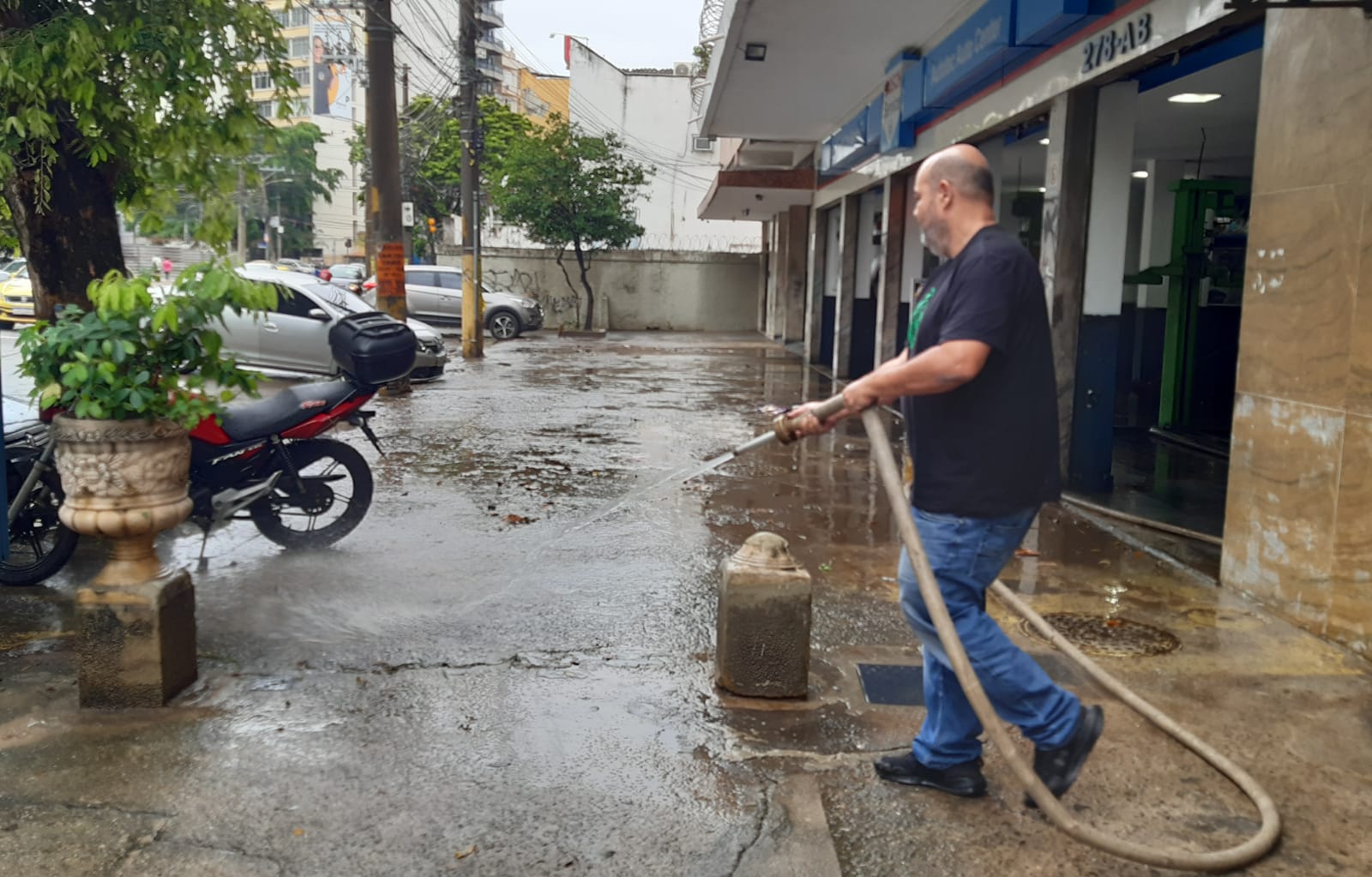 Comerciante limpando a calçada após chuva atingir o bairro do Maracanã