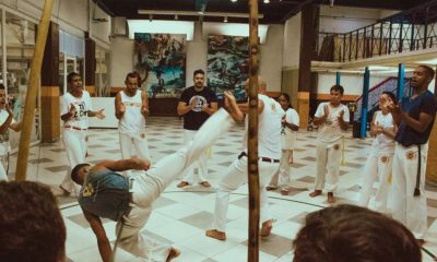 Na imagem, pessoas praticando capoeira