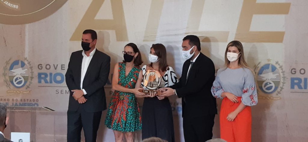 Castro, a Primeira Dama e o secretário entregando placas comemorativas