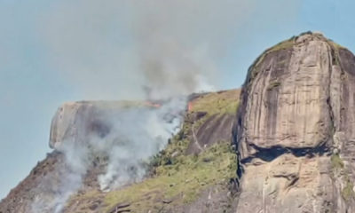 pedra da gávea pegando fogo e fumaça tomando conta do céu azul
