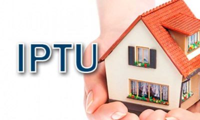 Figura de uma mão segurando uma casa com o nome IPTU