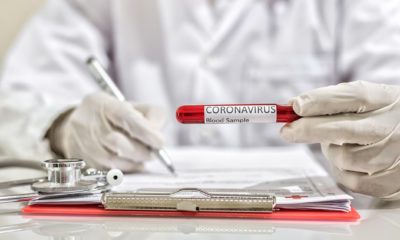 Profissional de saúde preenche ficha e segura tubo de ensaio com exame para detectar Covid-19