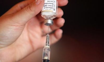 Mão de uma médica segurando um frasco de vacina